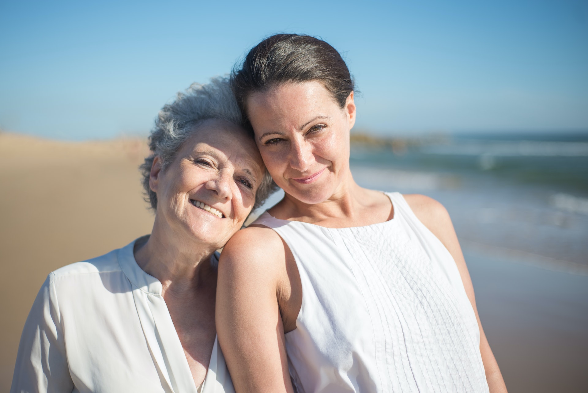 elderly mother smiling with her daughter at the beach